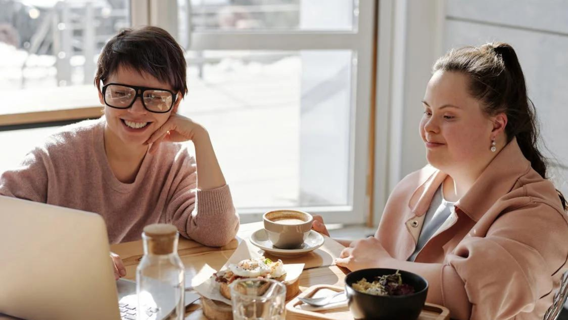 Two women, one with Down Syndrome, talk business at a cafe