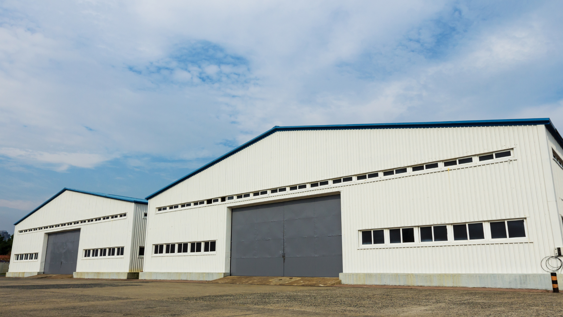 a large white industrial building with two garage doors