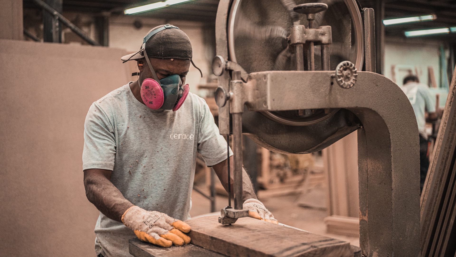 a man wearing a respirator working on a piece of wood on a machine